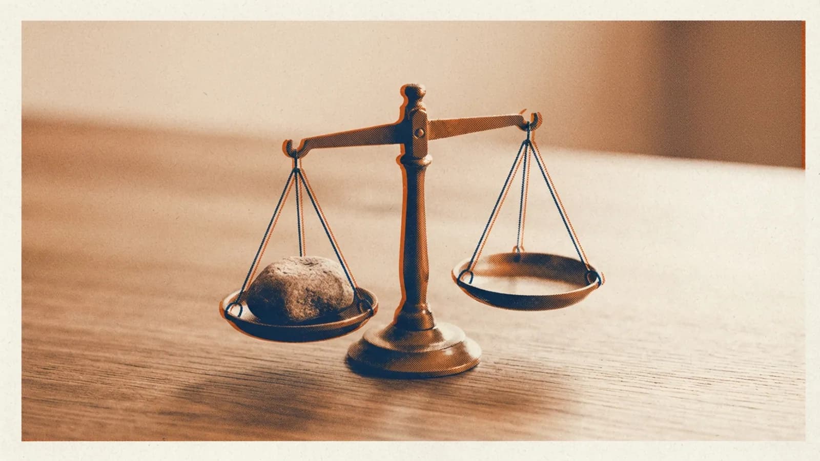 A small balance scale with a smooth stone on one pan, on a wooden surface.